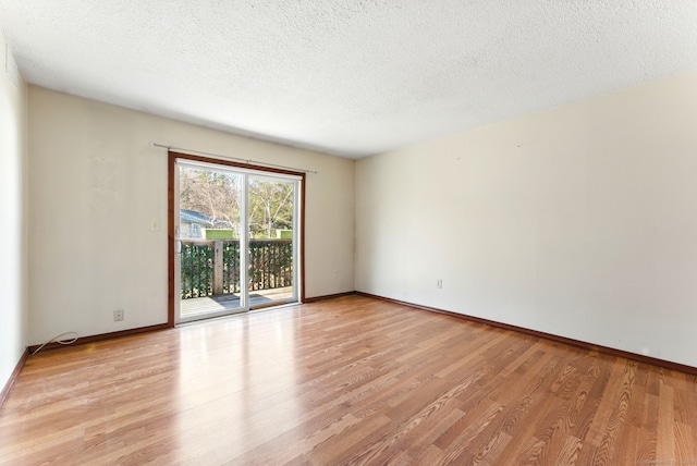 unfurnished room featuring light wood finished floors, a textured ceiling, and baseboards