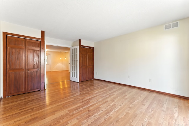 unfurnished bedroom with light wood finished floors, visible vents, french doors, and baseboards