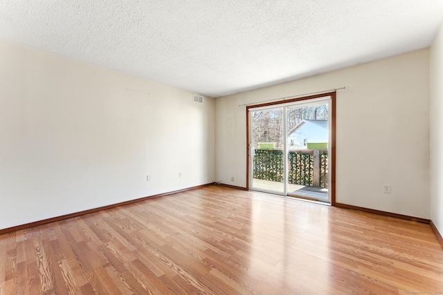 unfurnished room with baseboards, a textured ceiling, and light wood finished floors