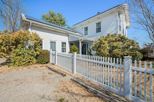 exterior space featuring a fenced front yard and roof mounted solar panels