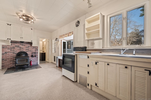 kitchen featuring a sink, light countertops, a wood stove, and range with electric stovetop