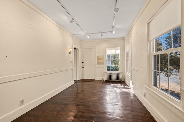 unfurnished room featuring radiator, dark wood-style floors, and track lighting