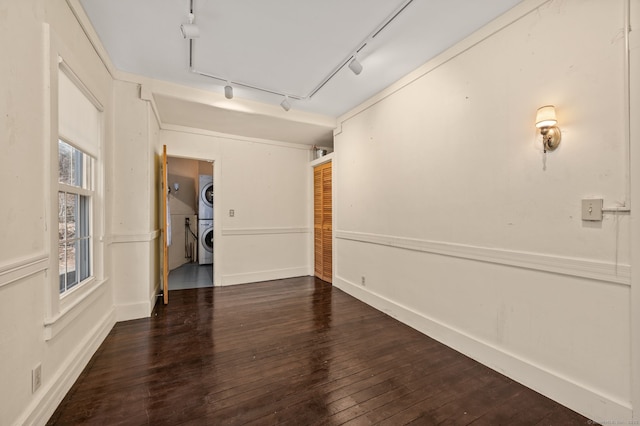unfurnished room featuring wood-type flooring and stacked washing maching and dryer