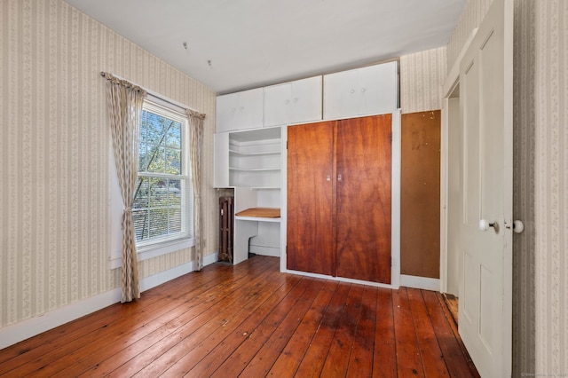 unfurnished bedroom with baseboards, hardwood / wood-style flooring, and wallpapered walls