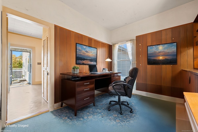 carpeted home office with wooden walls and baseboards