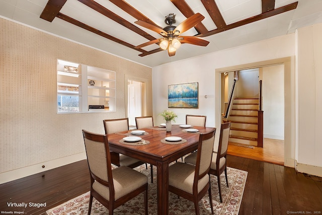 dining room with wallpapered walls, dark wood finished floors, stairway, beamed ceiling, and a ceiling fan
