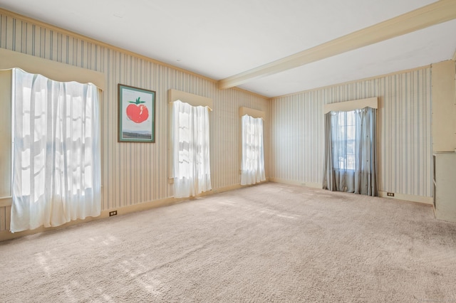 carpeted empty room featuring beamed ceiling