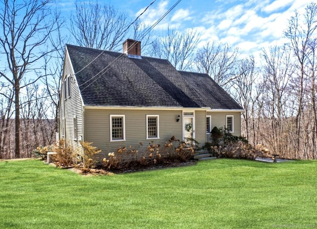 view of front facade with a chimney, a front lawn, and a shingled roof