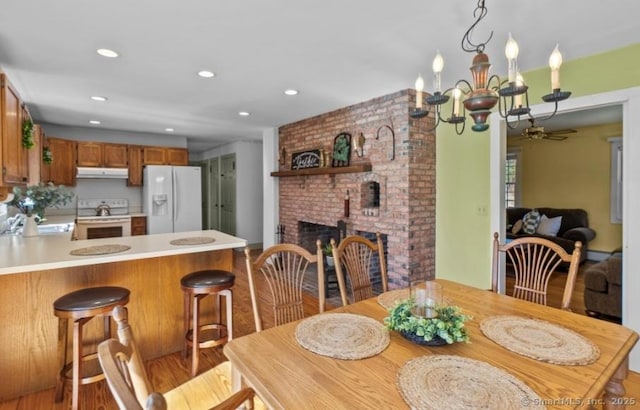 dining area with an inviting chandelier, recessed lighting, a fireplace, and wood finished floors