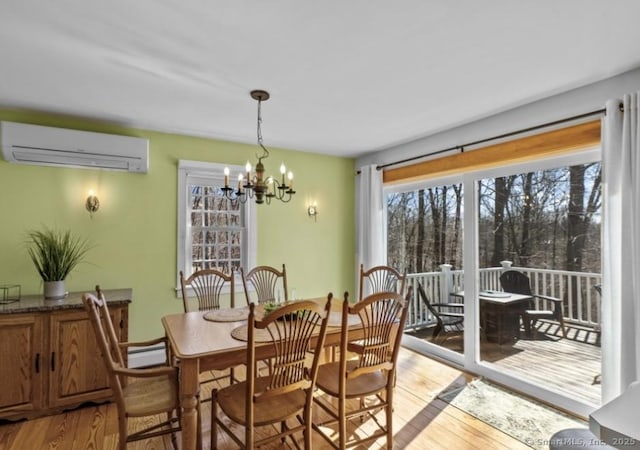 dining space with light wood-style flooring, a wall mounted air conditioner, and a chandelier