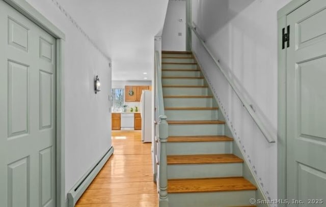 stairs with wood finished floors and baseboard heating