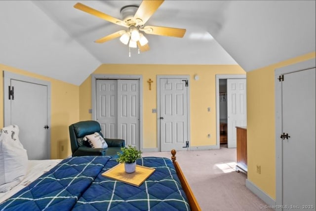 carpeted bedroom featuring baseboards, multiple closets, and lofted ceiling