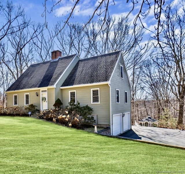 view of front of house featuring aphalt driveway, a front yard, a chimney, and an attached garage