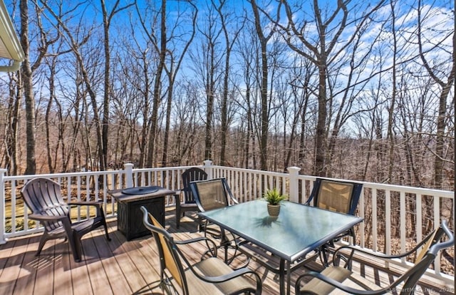 deck featuring outdoor dining area and a view of trees