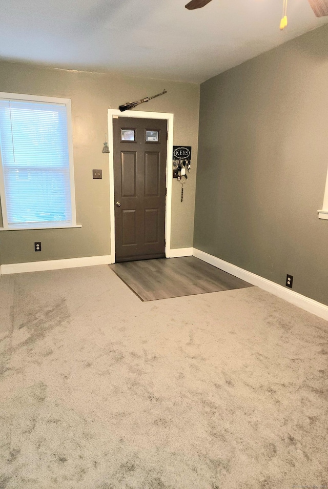 foyer entrance with baseboards, carpet floors, and ceiling fan