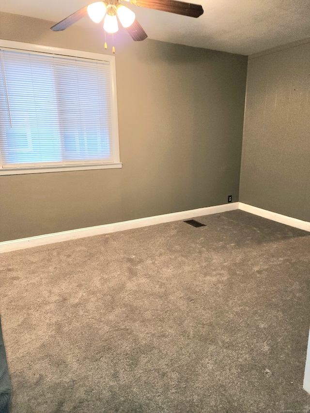 carpeted spare room featuring visible vents, a ceiling fan, and baseboards