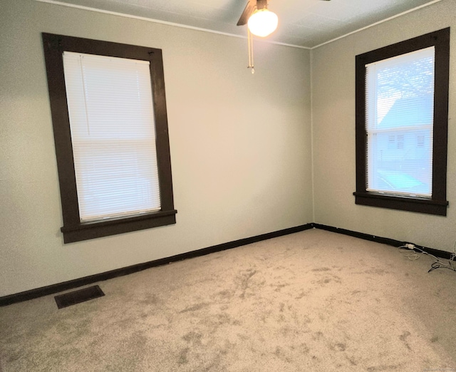 spare room with baseboards, visible vents, and light carpet