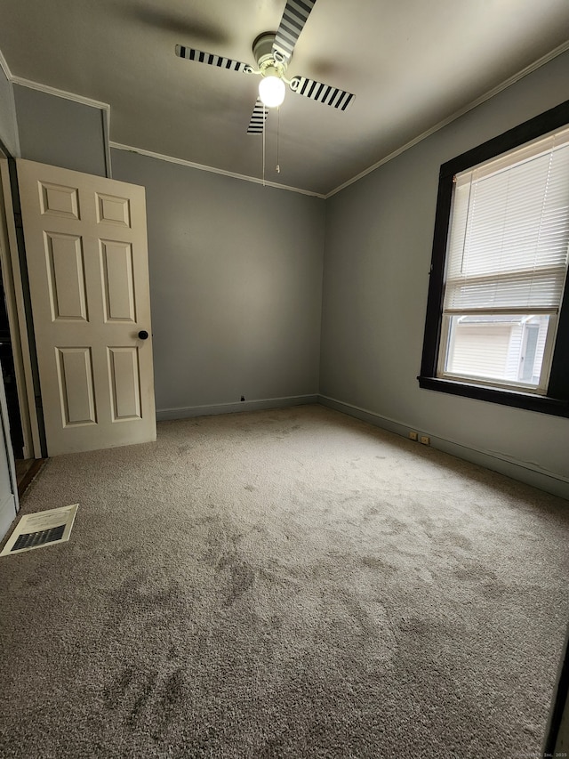 unfurnished room featuring visible vents, ceiling fan, baseboards, carpet, and ornamental molding