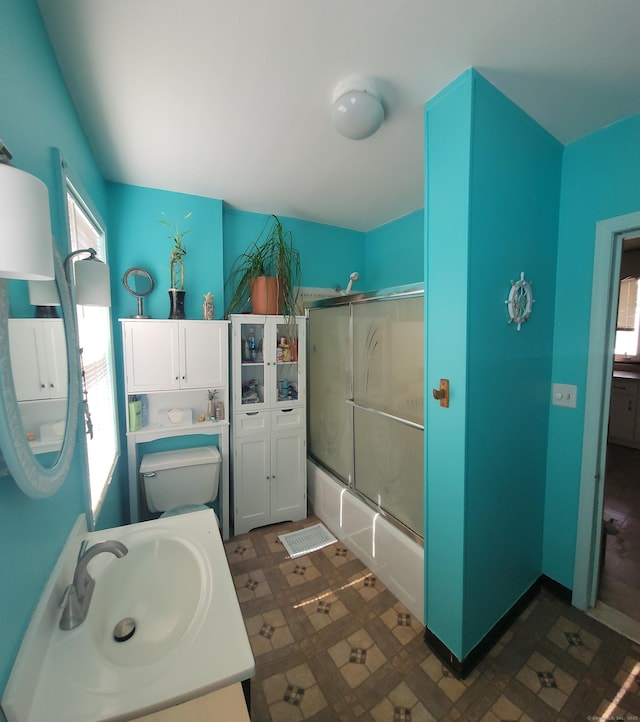 full bath featuring tile patterned floors, combined bath / shower with glass door, toilet, and a sink