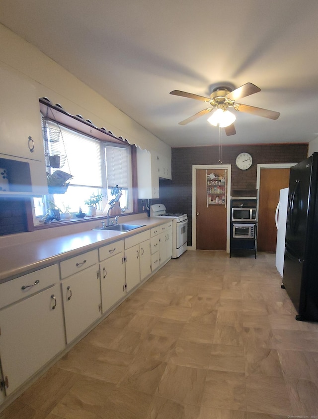 kitchen featuring a sink, white cabinetry, freestanding refrigerator, light countertops, and white gas range