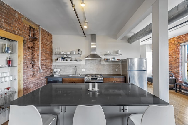 kitchen featuring open shelves, wall chimney range hood, dark countertops, and stainless steel appliances