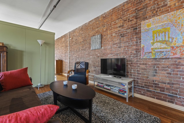 living area with brick wall and wood finished floors