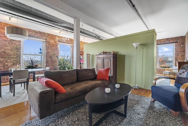 living area featuring wood finished floors and brick wall