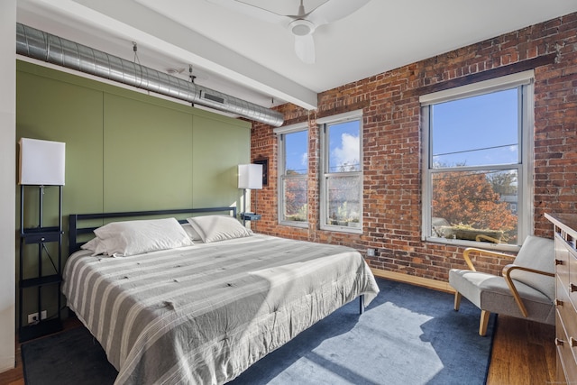 bedroom featuring beam ceiling, brick wall, and a ceiling fan