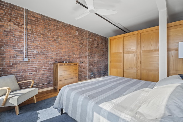 bedroom featuring ceiling fan and brick wall