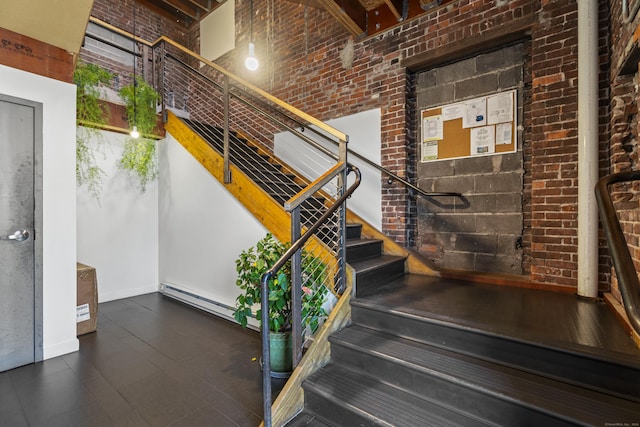 stairway featuring brick wall and a baseboard radiator