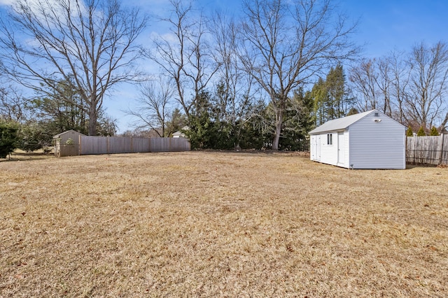 view of yard with a storage unit, an outbuilding, and fence