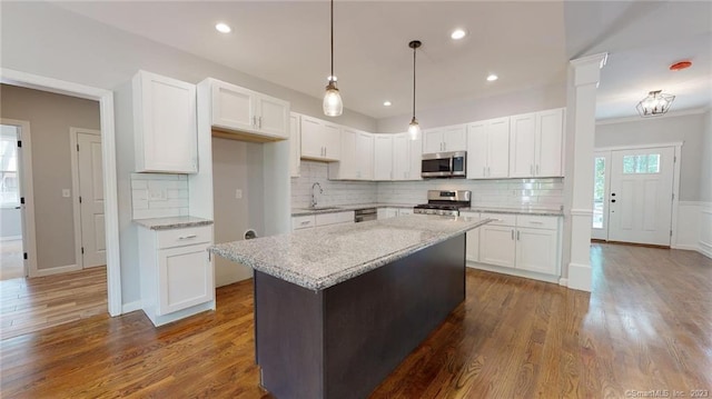 kitchen featuring light stone counters, dark wood-style flooring, a sink, stainless steel appliances, and white cabinetry