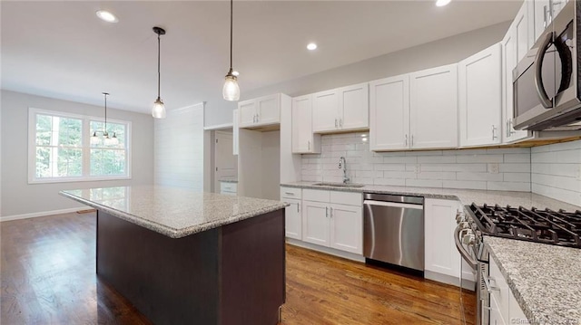 kitchen with wood finished floors, light stone countertops, stainless steel appliances, and a sink