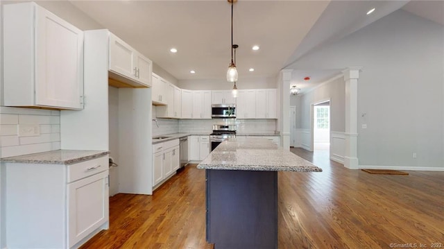 kitchen featuring light stone counters, a sink, wood finished floors, white cabinetry, and appliances with stainless steel finishes