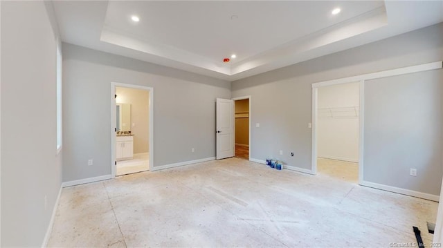 unfurnished bedroom with recessed lighting, baseboards, and a tray ceiling