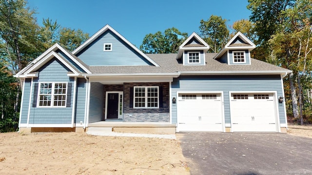 view of front facade featuring aphalt driveway, roof with shingles, and an attached garage