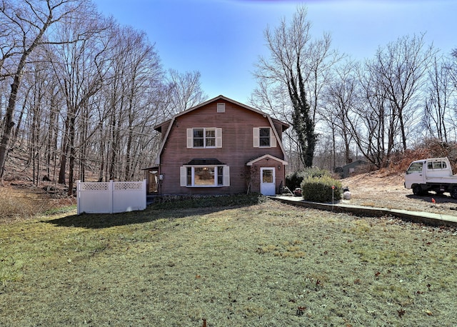 dutch colonial with a front yard, fence, and a gambrel roof