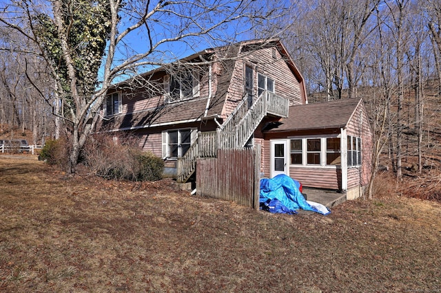 exterior space with a gambrel roof, roof with shingles, and a sunroom