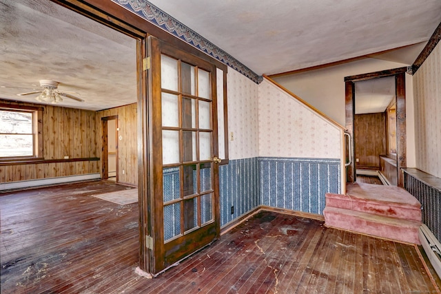 spare room with wallpapered walls, a baseboard heating unit, wood-type flooring, and wainscoting