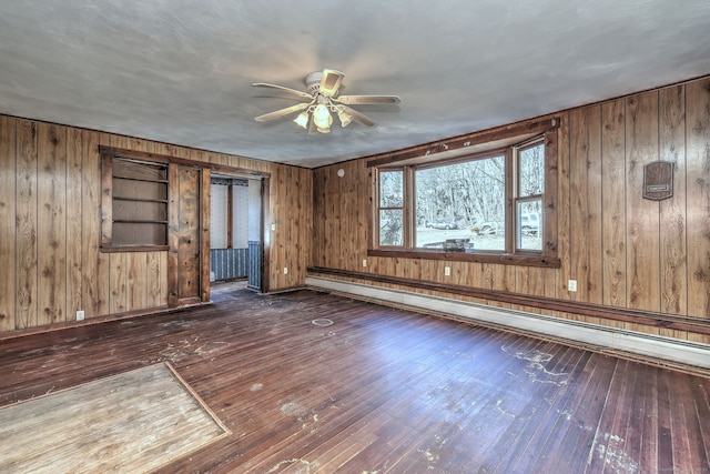 unfurnished room featuring baseboard heating, wood walls, ceiling fan, and hardwood / wood-style flooring