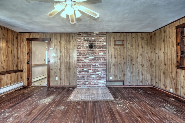 unfurnished room featuring wooden walls, a baseboard radiator, a textured ceiling, and hardwood / wood-style floors