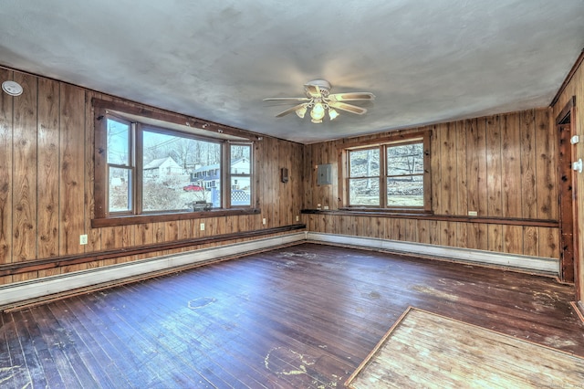 unfurnished room featuring wood walls, a baseboard radiator, a ceiling fan, and wood-type flooring