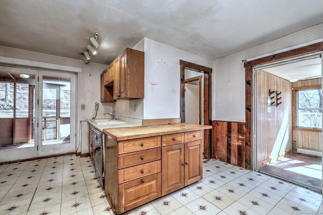 kitchen featuring a sink, light floors, butcher block counters, and wallpapered walls