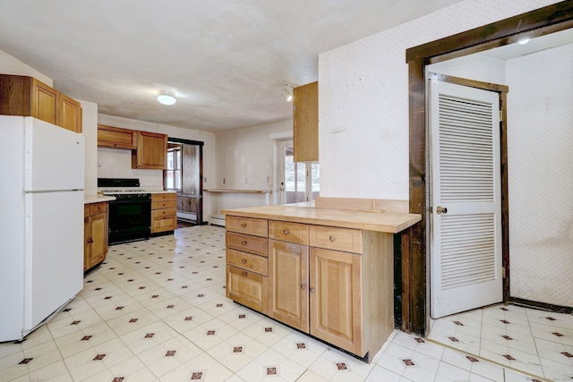 kitchen featuring gas stove, wallpapered walls, light floors, and freestanding refrigerator