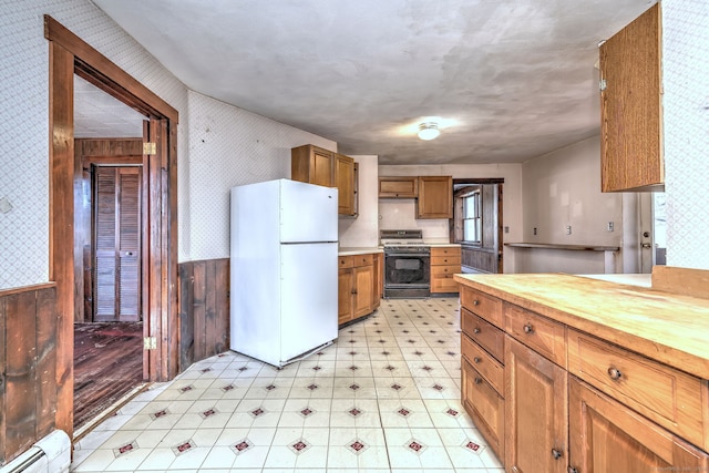 kitchen featuring wallpapered walls, a wainscoted wall, butcher block counters, gas range oven, and freestanding refrigerator