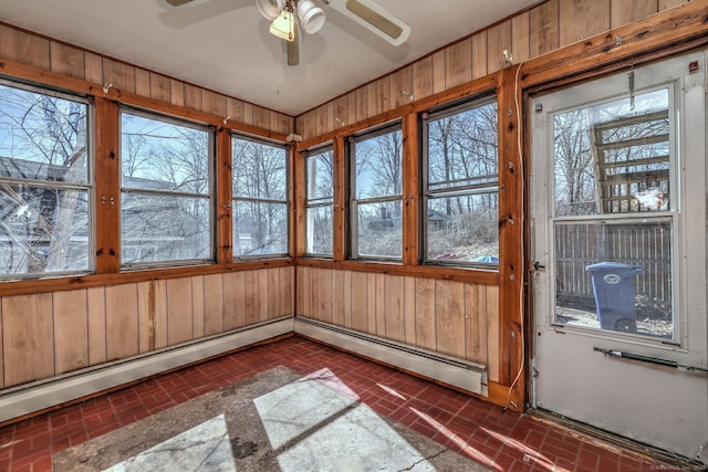 unfurnished sunroom featuring ceiling fan, a healthy amount of sunlight, and a baseboard radiator