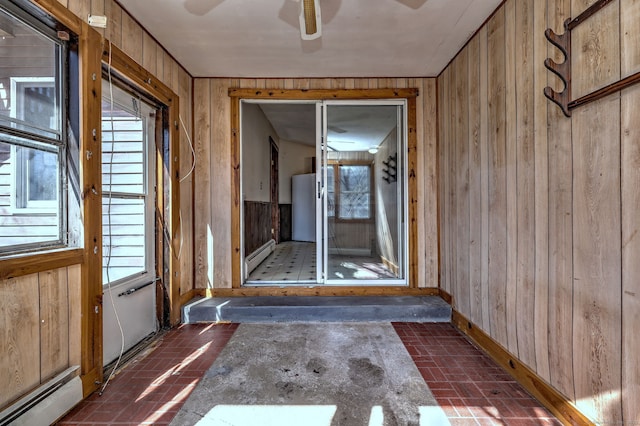 interior space featuring brick floor, baseboard heating, a healthy amount of sunlight, and wooden walls