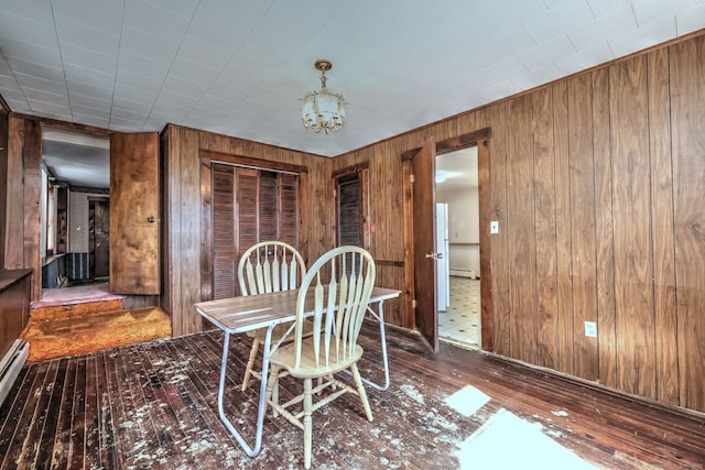 dining area featuring a chandelier, wooden walls, and hardwood / wood-style floors