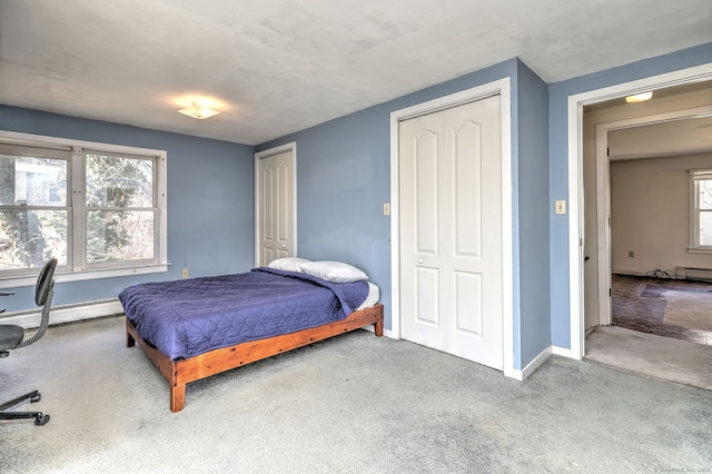 carpeted bedroom featuring baseboards, multiple closets, and baseboard heating