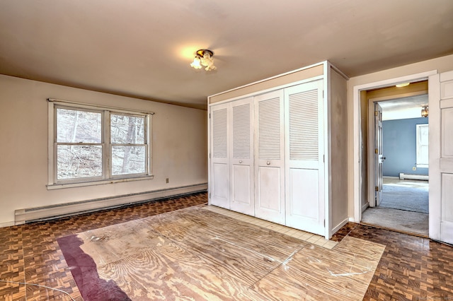 unfurnished bedroom featuring a closet, baseboards, and a baseboard radiator